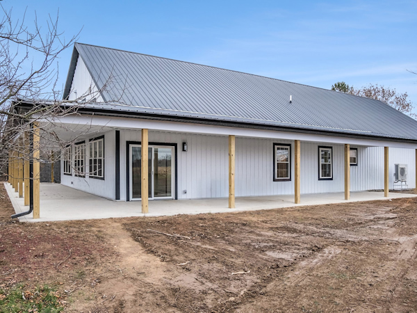 Modern barndominium exterior featuring a wrap-around porch